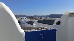 A rooftop with white buildings and a blue utility box. - Amphora Charm Suite - Akrotiri Escape (Santorini)