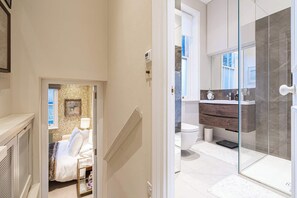 A modern bathroom with a glass shower, a white toilet, and a wooden vanity. - Lovely 1 Bedroom Flat in Chelsea (London)