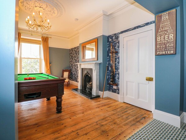 Une pièce avec une table de billard, une cheminée et un mur orné d’une enseigne sur le thème de la bière.