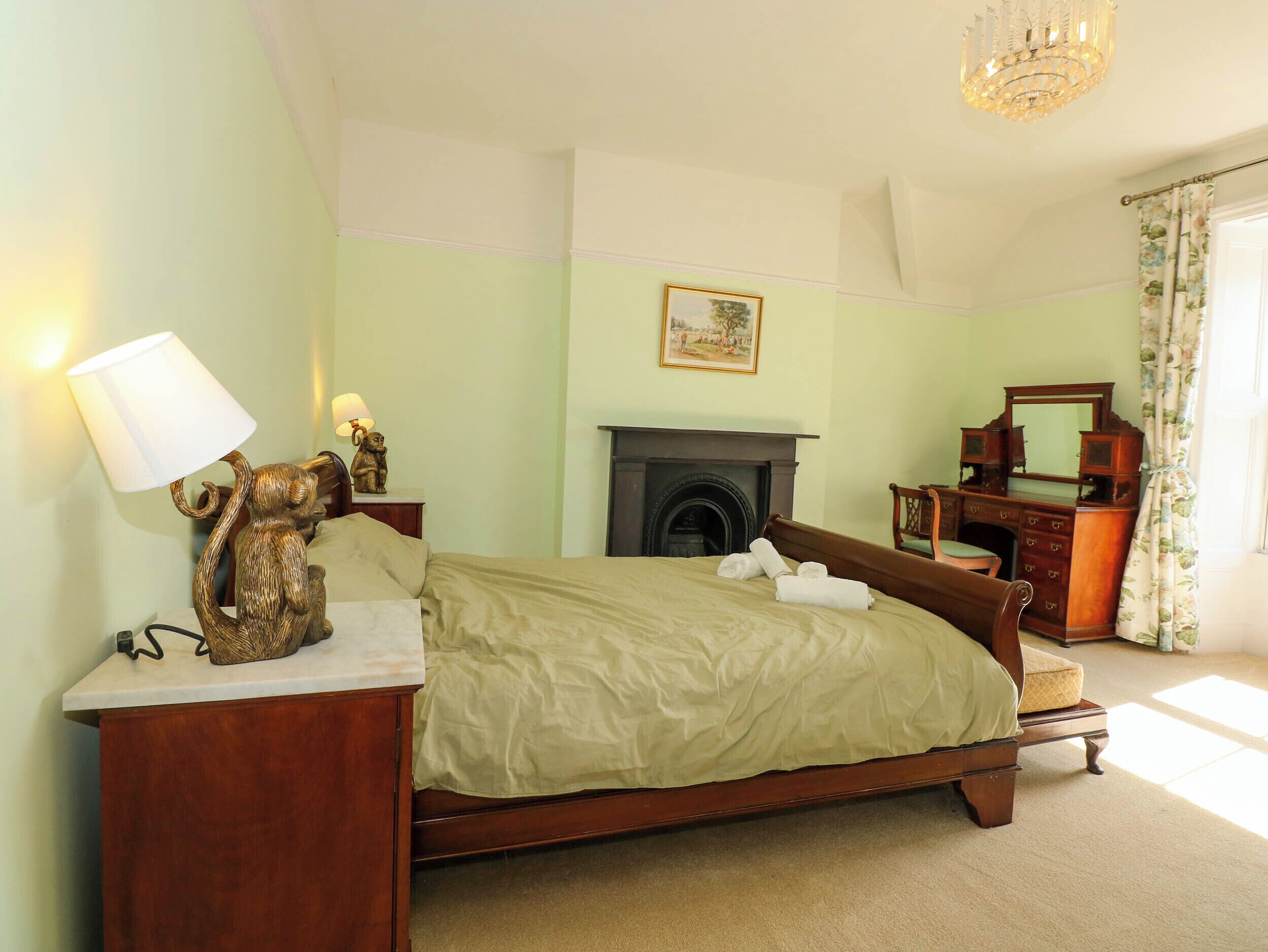 A bedroom with a bed, bedside table, lamp, and dresser.