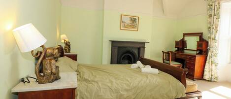 A bedroom with a bed, bedside table, lamp, and dresser.