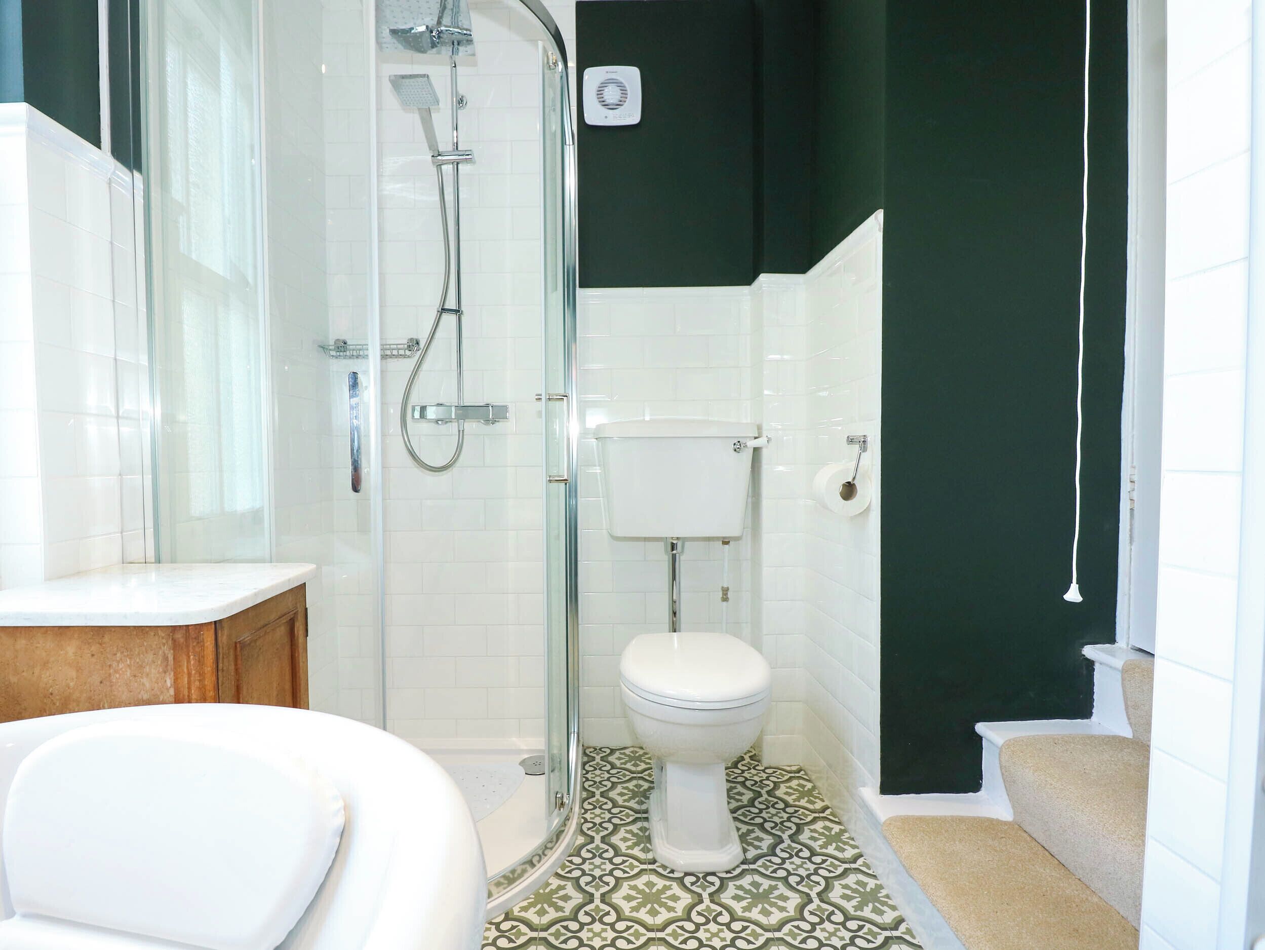 Une salle de bain avec une douche à parois de verre, des toilettes blanches et un lavabo blanc.