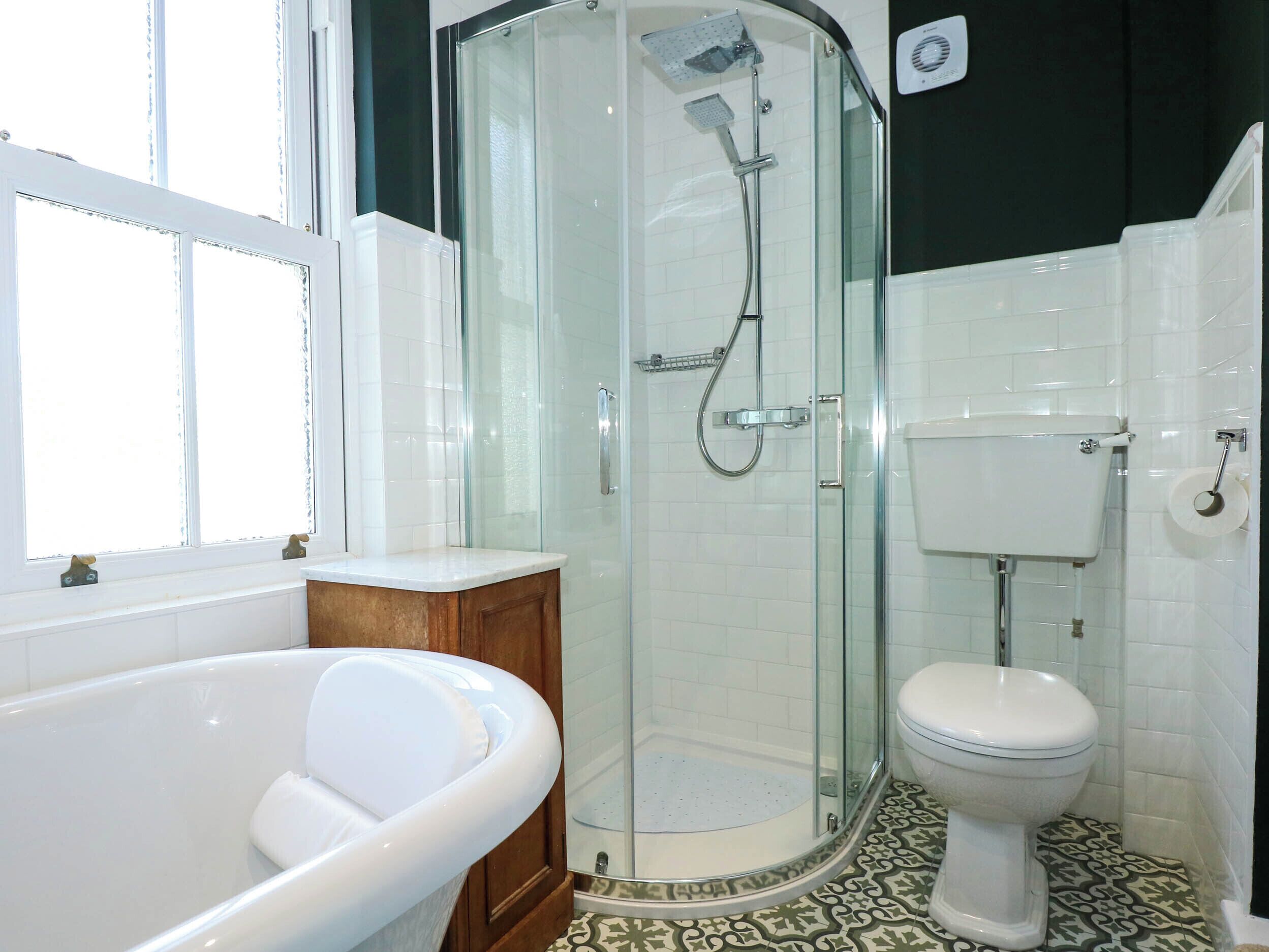 Un baño con ducha envuelta en vidrio, inodoro blanco y bañera independiente.