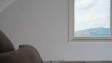 Una stanza con un letto, una finestra vista montagna e una porzione di parete.