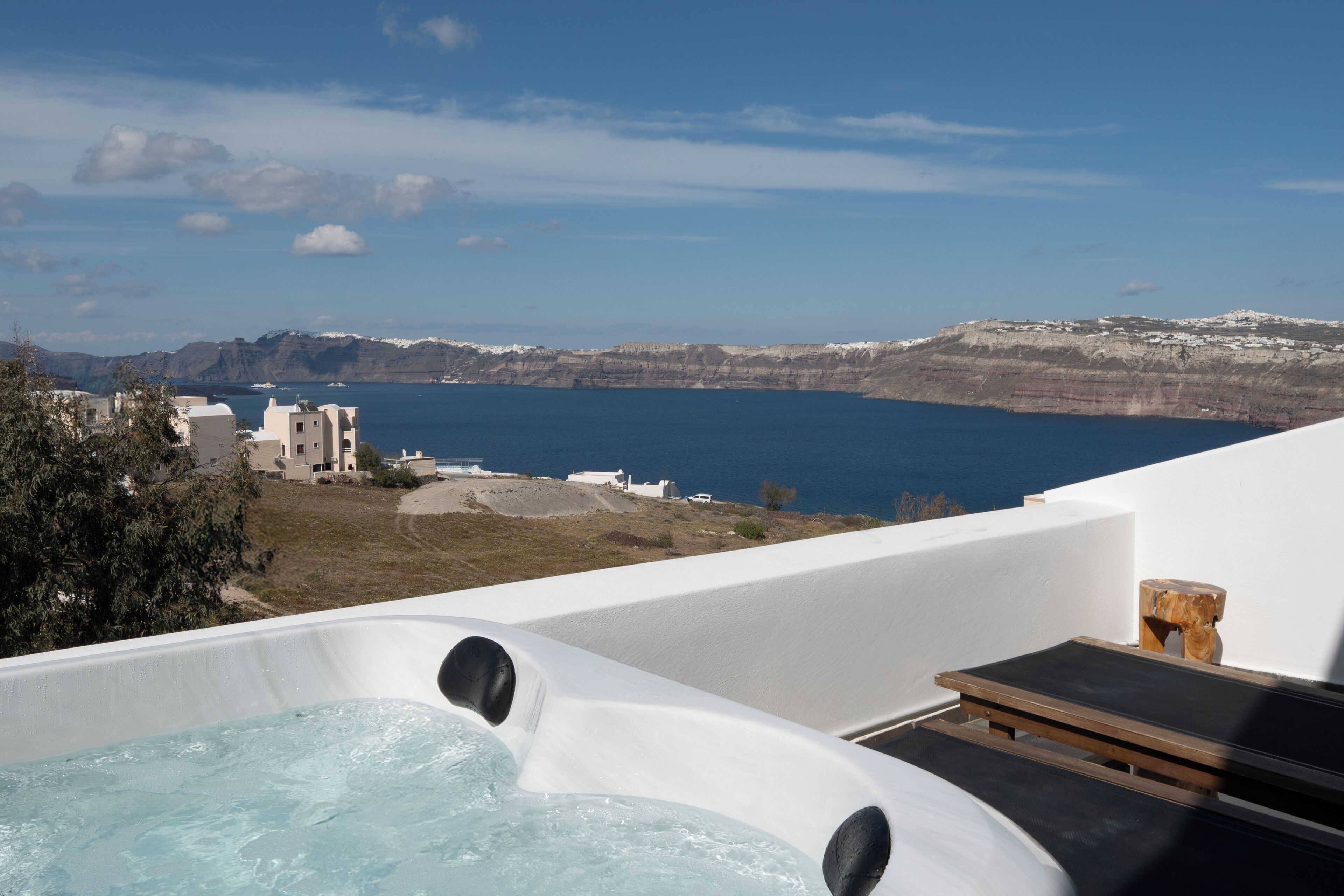 A hot tub with a view of the sea and buildings in the background.
