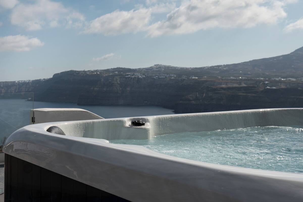 A hot tub with a view of a cliff and water body.
