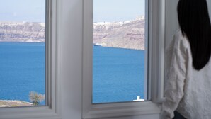 A room with a large window overlooking a body of water and cliffs. - Zen Villas (Akrotiri)