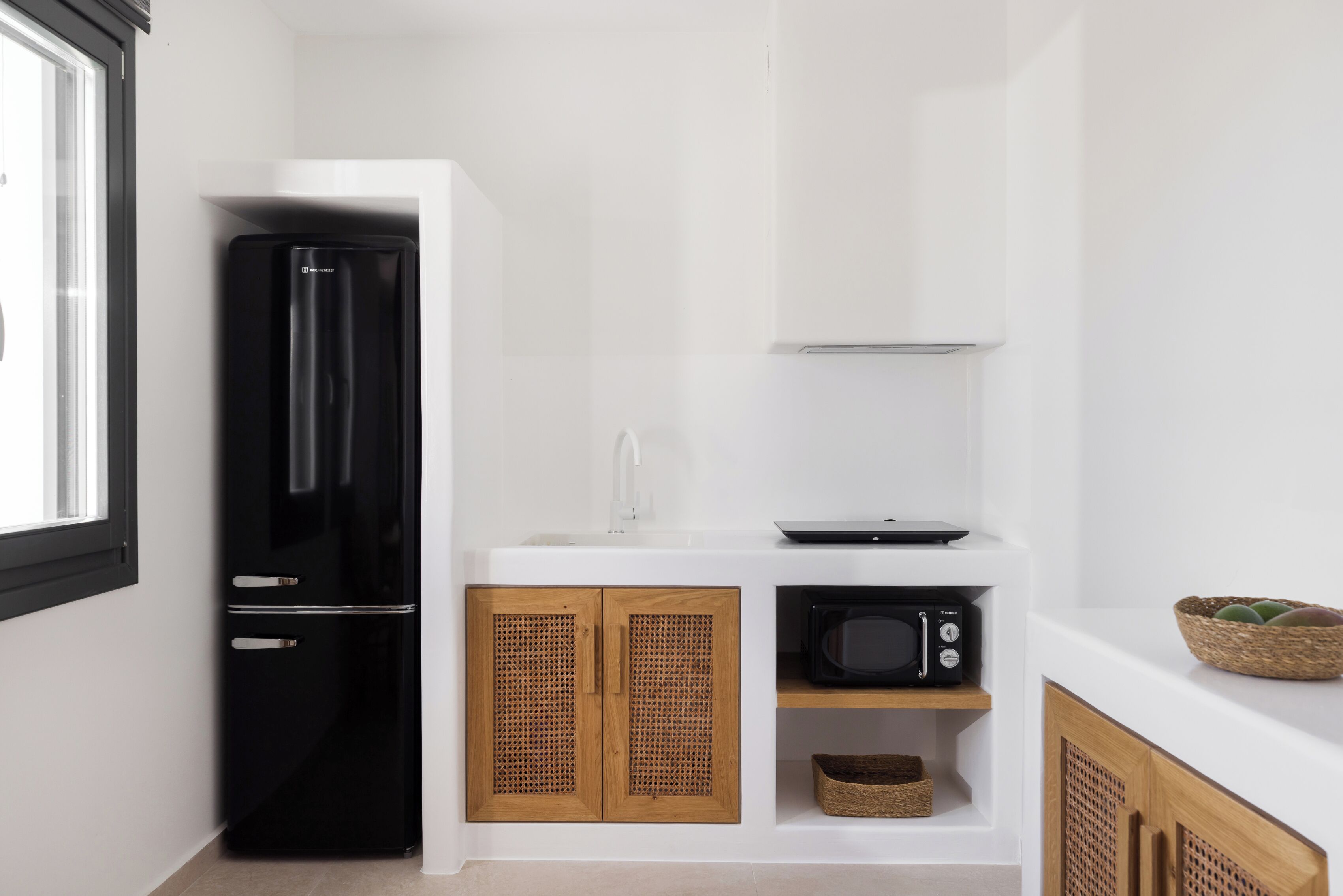 A compact kitchen with a black refrigerator, a microwave, and wooden cabinets.
