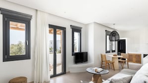 Un salon moderne avec un canapé, une table basse et un téléviseur. Il y a également un coin repas avec des chaises et une table.