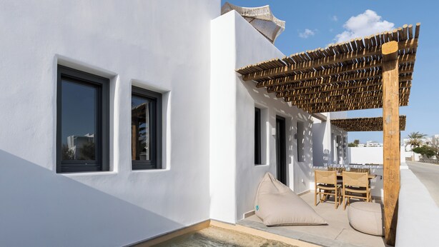 Un espace piscine extérieur moderne, agrémenté d’une pergola, de sièges et offrant une vue sur la mer.