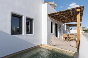 A modern outdoor pool area with a pergola, seating, and a view of the sea. - Solmar Suites (Naxos)