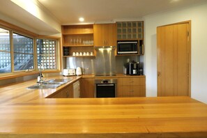 A modern kitchen with wooden cabinets, stainless steel appliances, and a large wooden countertop. - Bridgecroft Bungalow (Richmond)