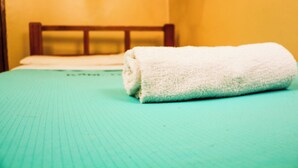 A bed with a green sheet and a white towel. - Kisumu Travelers Hotel (Kisumu)
