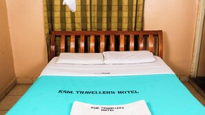 A single bed with a wooden headboard and white bedding in a room with a green curtain. - Kisumu Travelers Hotel (Kisumu)