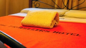 A bed with a yellow towel and a red bedspread with "TRAVELER'S HOTEL" text. - Kisumu Travelers Hotel (Kisumu)
