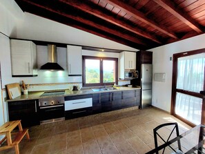 Una cocina moderna con una isla grande, electrodomésticos integrados y vistas al exterior.