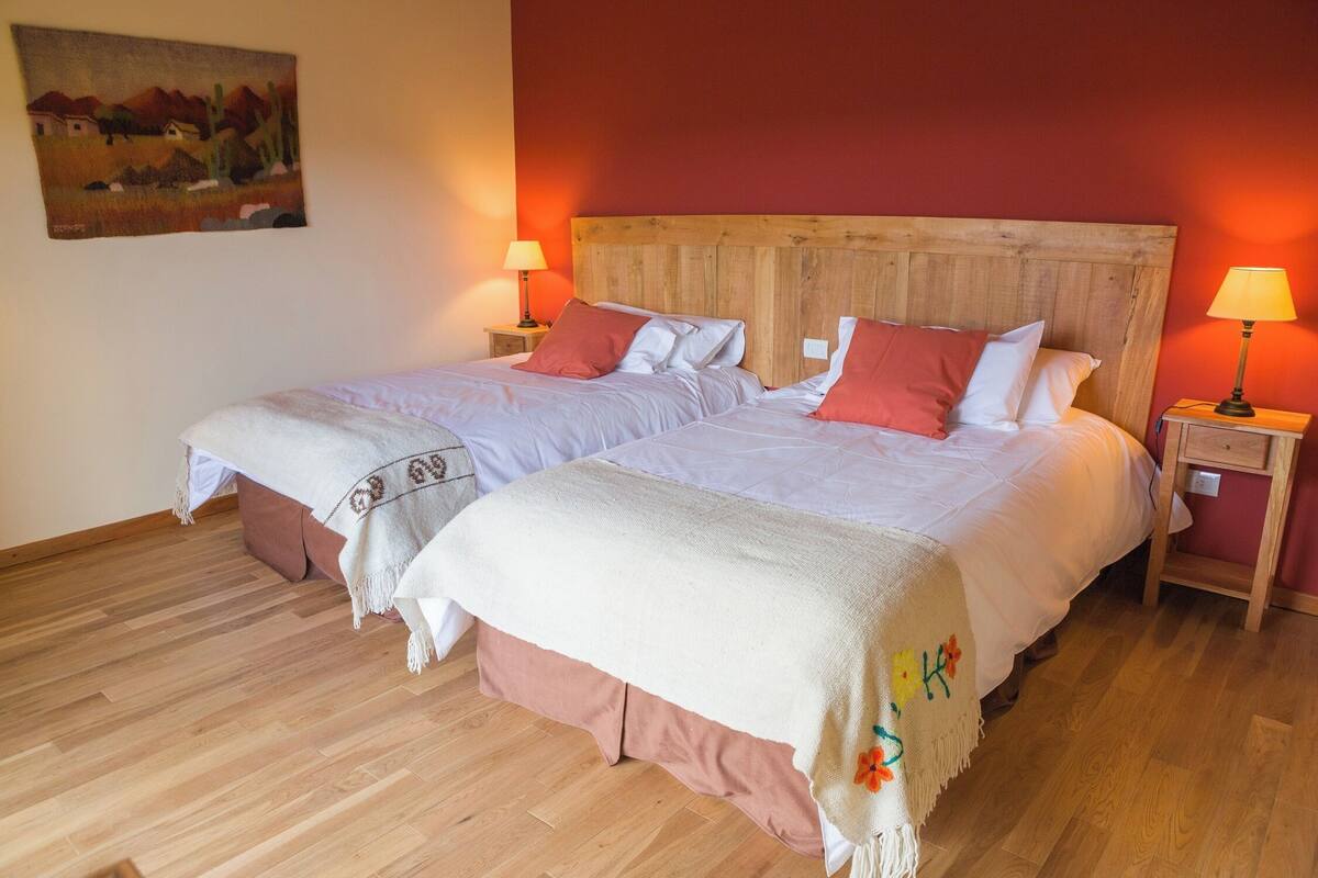 A double bed with a wooden headboard, two bedside tables with lamps, and a painting on the wall.