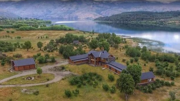 A rural property with a large house and several smaller buildings, surrounded by fields and a lake. - Lago Rosario Lodge (Trevelin)