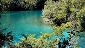 A natural landscape with a clear turquoise lake surrounded by dense green forest. - Lago Rosario Lodge (Trevelin)