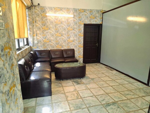 Una habitación con un sofá modular, una mesita de centro y piso de baldosas.