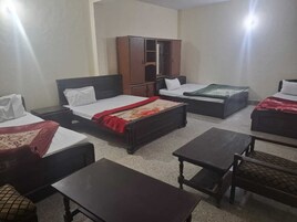 Una habitación de hotel con dos camas individuales, un armario, una mesita y una silla.