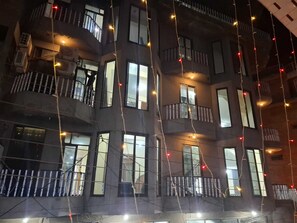 Un edificio de varios pisos con balcones y ventanas, algunas adornadas con luces colgantes.