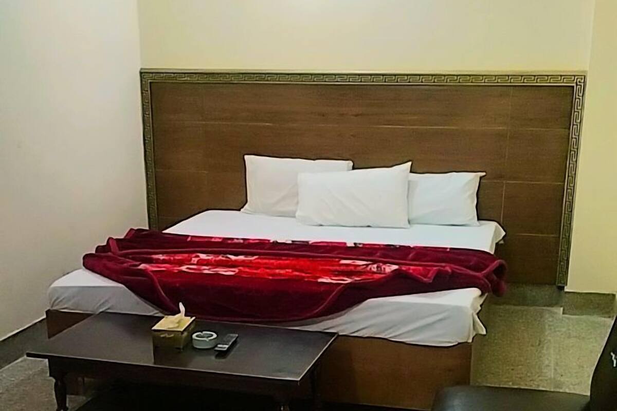 Un dormitorio con una cama, una mesita, una silla y una mesita de noche.