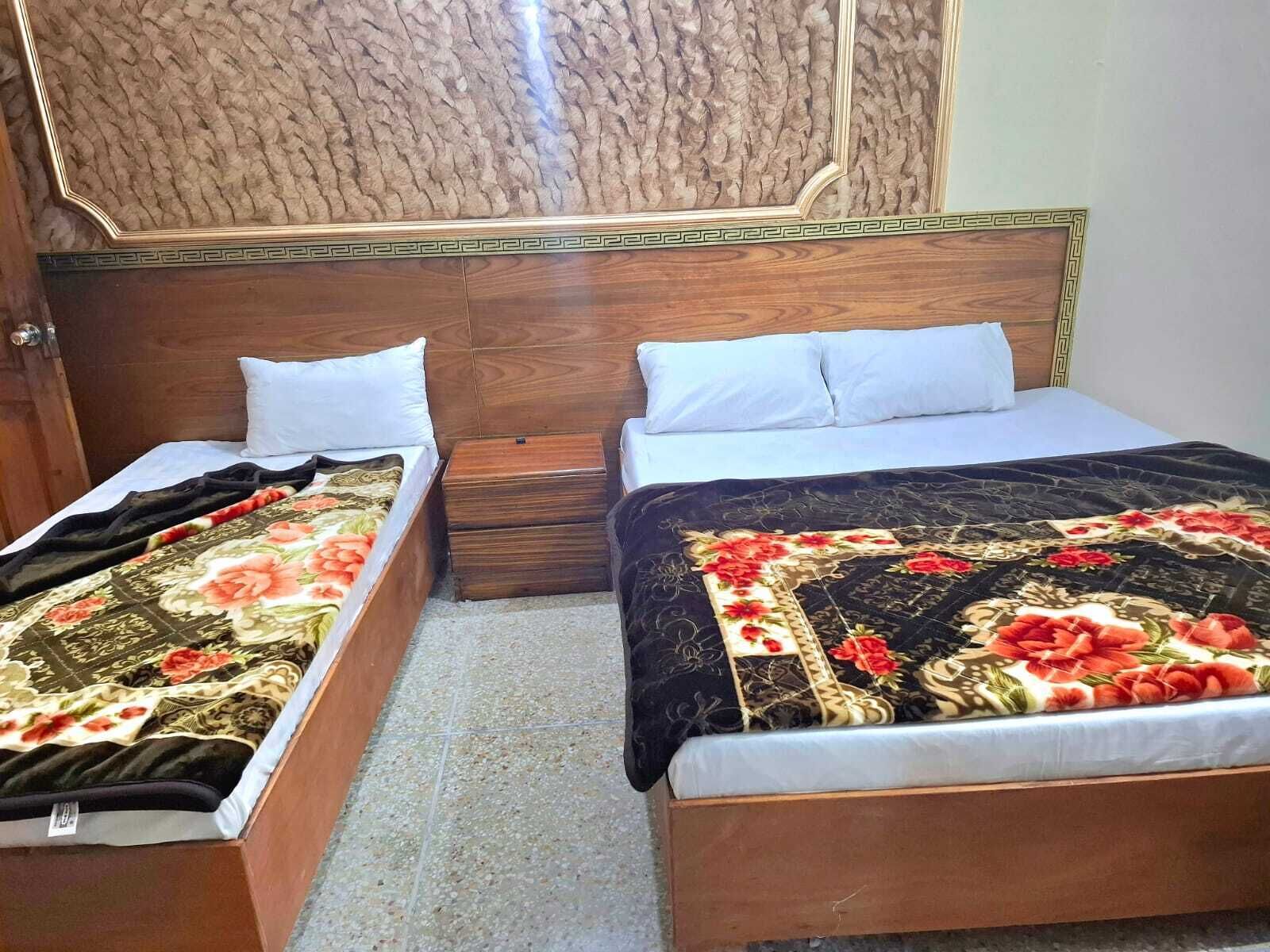 Two single beds with wooden headboards, white pillows, and floral bedding.