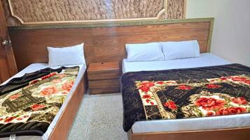 Two single beds with wooden headboards, white pillows, and floral bedding.