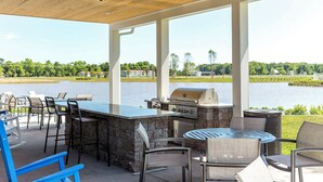 An outdoor patio with a grill, seating, and a view of a lake. - 4 BR Beauty-Millville by the Sea~ Minutes to Bethany Beach -23548 Bonfire Way (Millville)