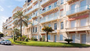 Een meerlaags hotel met balkons, een verzorgd gazon en een geparkeerde auto.