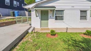 A single-story house with a green door, number 1300, and a small front yard with grass and a flower bed. - Fully Furnished 2BR Near Duke & VA Hospital Ideal for Medical & Extended Stays (Durham)