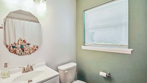 A bathroom with a white sink, a toilet, and a window with blinds. - Fully Furnished 2BR Near Duke & VA Hospital Ideal for Medical & Extended Stays (Durham)