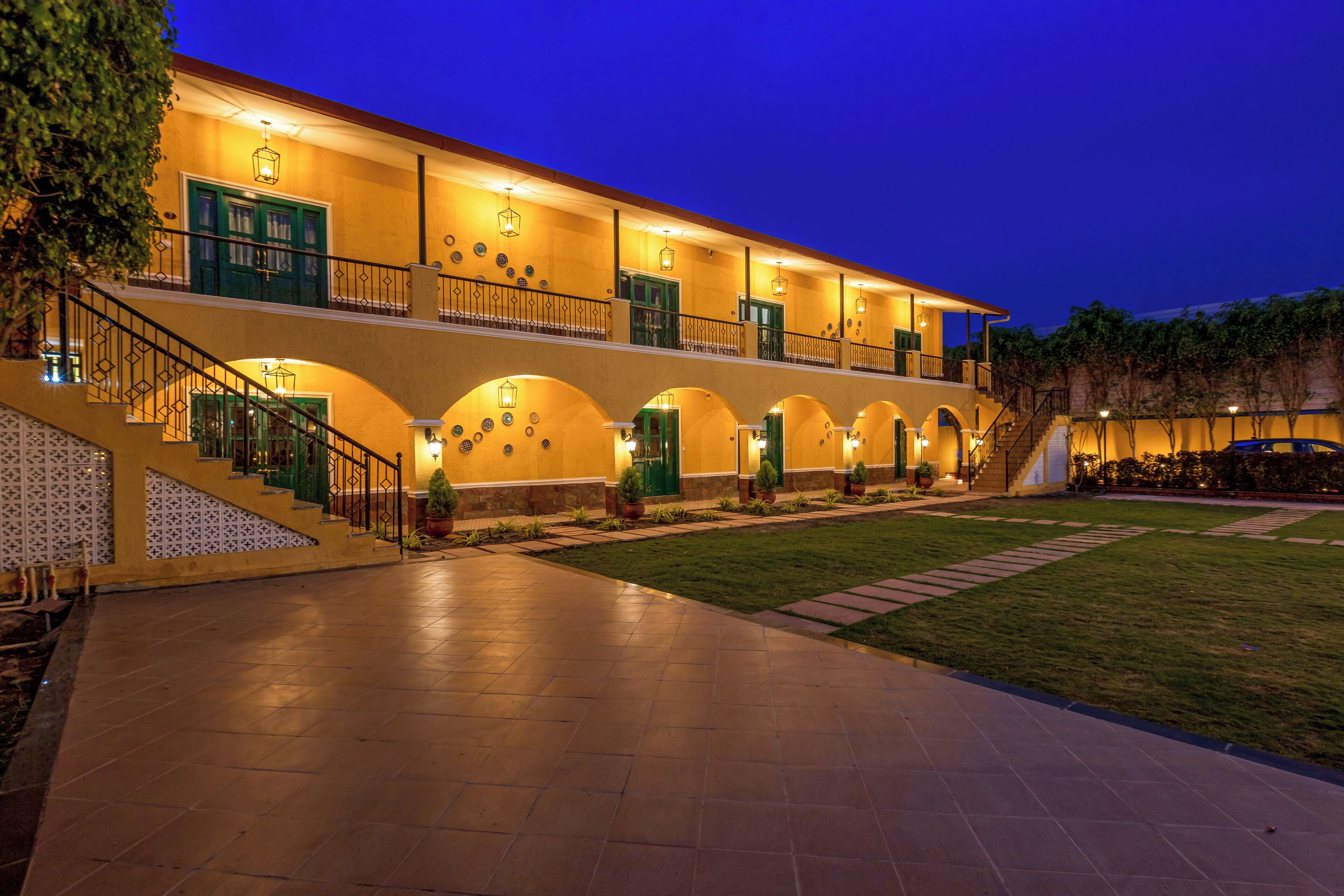 Un hotel de dos pisos, con varios balcones y una entrada bien iluminada.