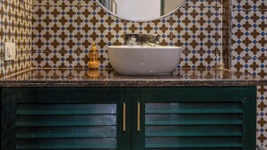 A bathroom with a round mirror, a sink, and a green cabinet. - Greenfields Resort (Bhopal)
