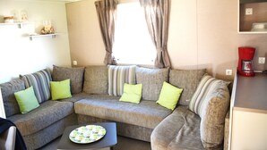 A living room with a sectional sofa, a coffee maker, and a window with curtains.