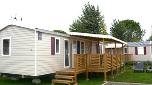 A single-story mobile home with a covered porch and a small deck.