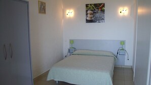 Ein Schlafzimmer mit einem Bett, Nachttischlampen, einem Wandbild und einem Schrank.