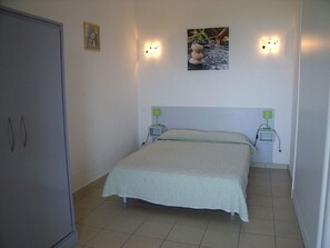 Un dormitorio con cama, lámparas de noche, un cuadro en la pared y un armario.