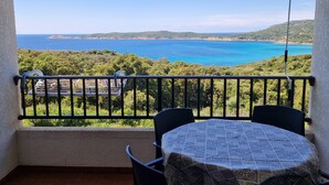 Ein Balkon mit Tisch und Stühlen mit Blick auf die Küste und einen klaren Himmel.
