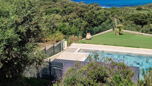 Zona de piscina con vista al mar y una isla distante.