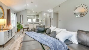 Una sala de estar moderna con un sofá, un comedor y una cocina al fondo.