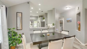Un comedor moderno con una mesa de madera oscura, sillas blancas y una superficie de cristal.