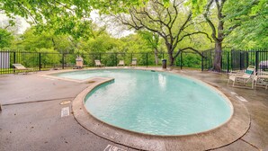 A swimming pool with a curved edge, surrounded by a black metal fence and several lounge chairs. - 9 Mi to Dtwn Dallas: Cozy Couple's Getaway (Dallas)