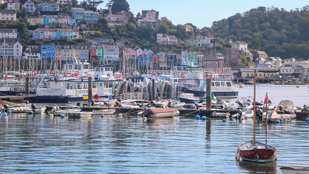 A harbor with various boats docked, surrounded by colorful houses and a hillside in the background. - 8 Dartmouth House (Dartmouth)