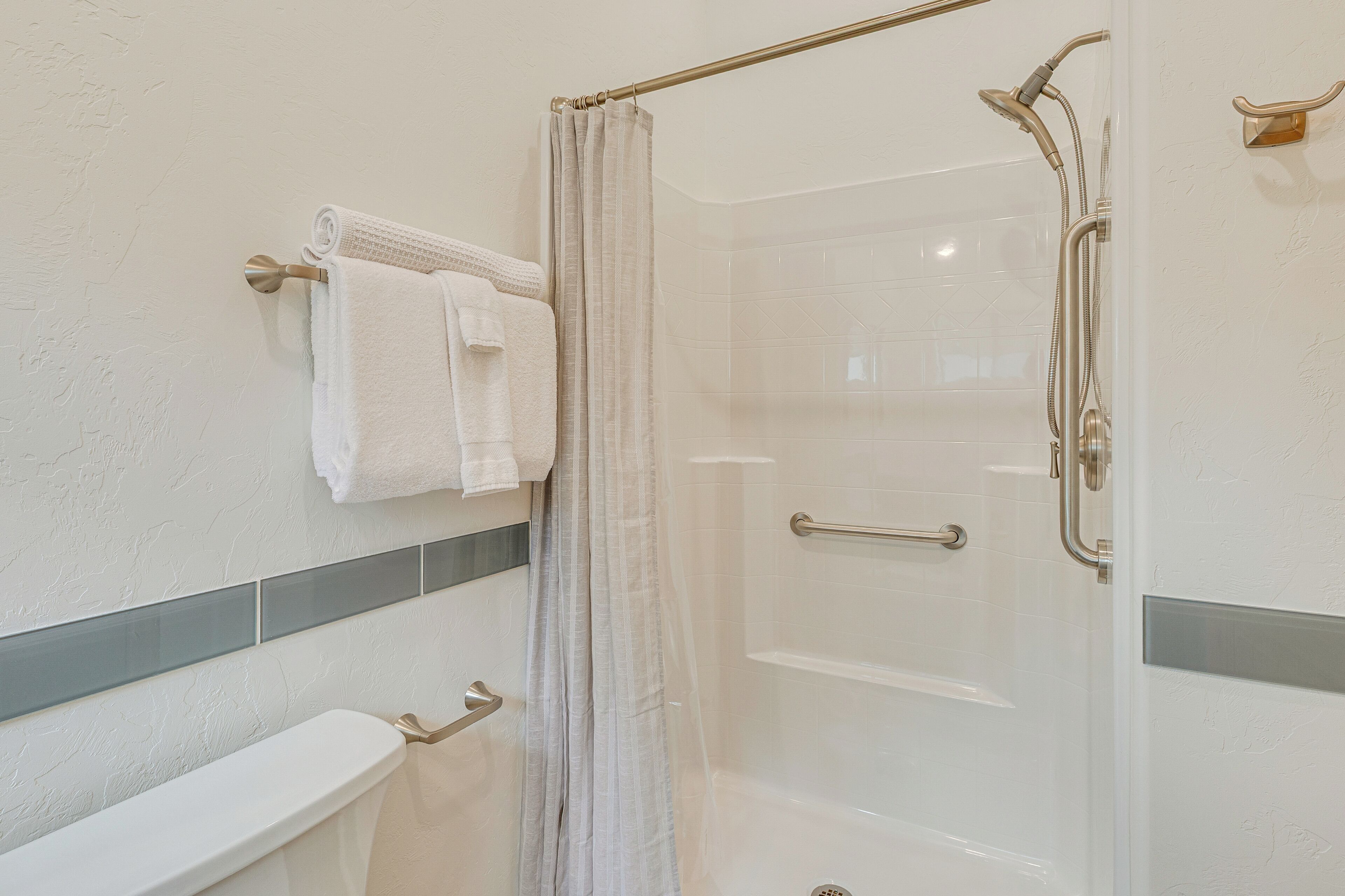 Une salle de bain avec une douche à parois de verre, des toilettes et un porte-serviettes avec deux serviettes blanches.