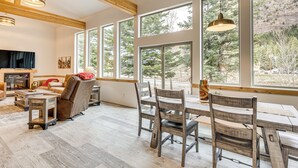A spacious living room with a fireplace, large windows, and a dining area with wooden furniture. - On-site River Access: Mtn-view Ouray Oasis! (Ouray)