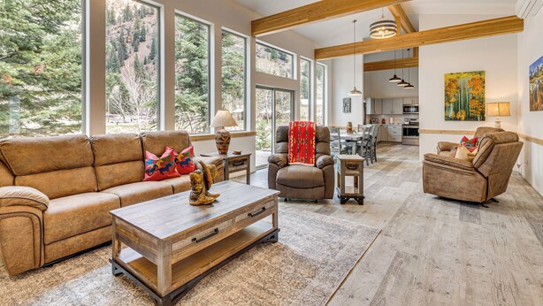 A spacious living room with large windows, a wooden ceiling, and a cozy seating area. - On-site River Access: Mtn-view Ouray Oasis! (Ouray)