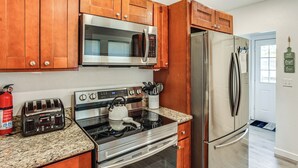 A kitchen with wooden cabinets, stainless steel appliances, a toaster, and a kettle.