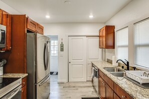 A kitchen with wooden cabinets, stainless steel appliances, granite countertops, and a double sink. - 4 Mi to Several Museums: Quaint Tacoma Home (Tacoma)